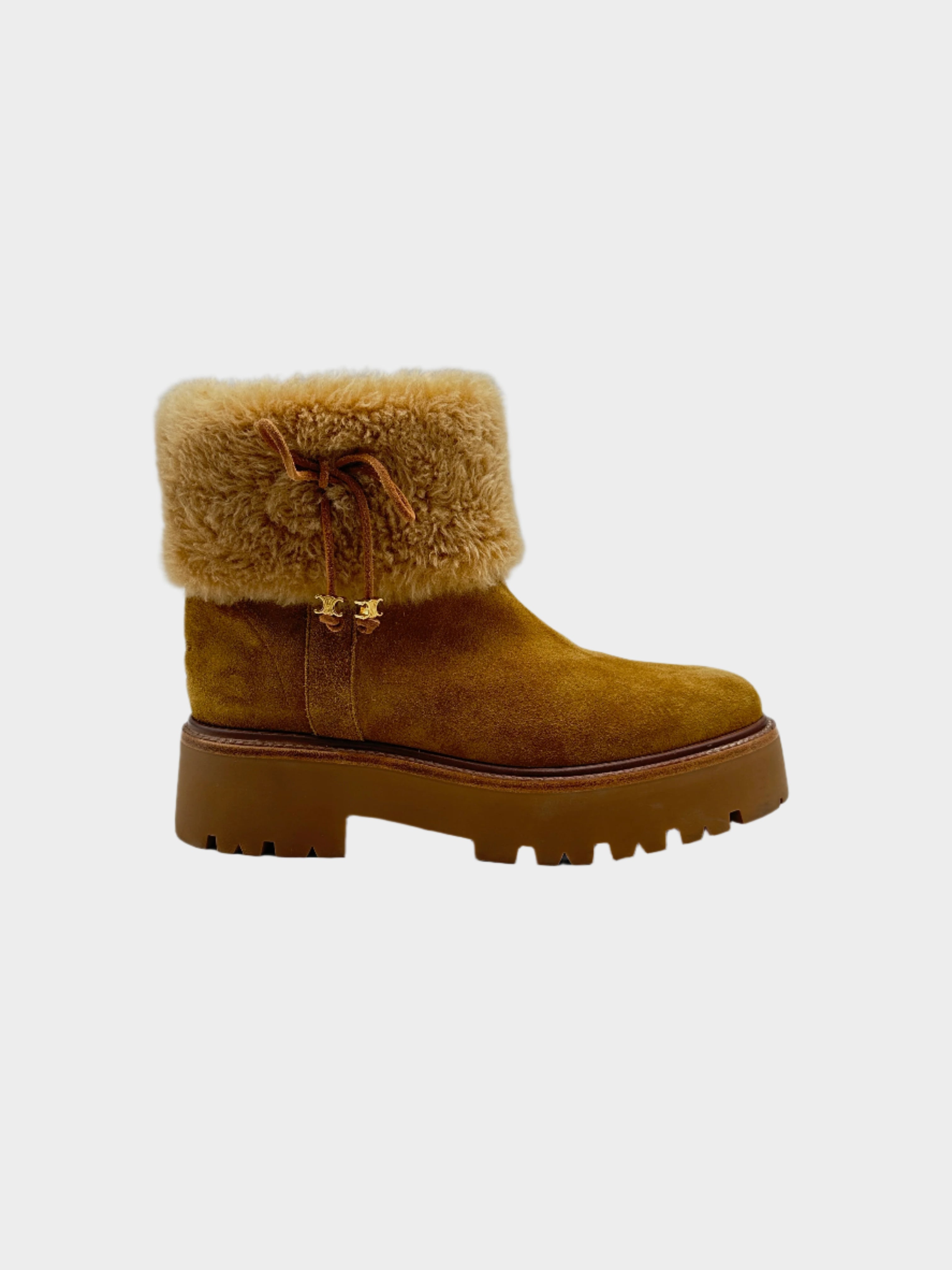 Stivaletto Celine Teddy in suede marrone con fodera in shearling e dettagli dorati. Suola carrarmato per comfort e stile invernale.