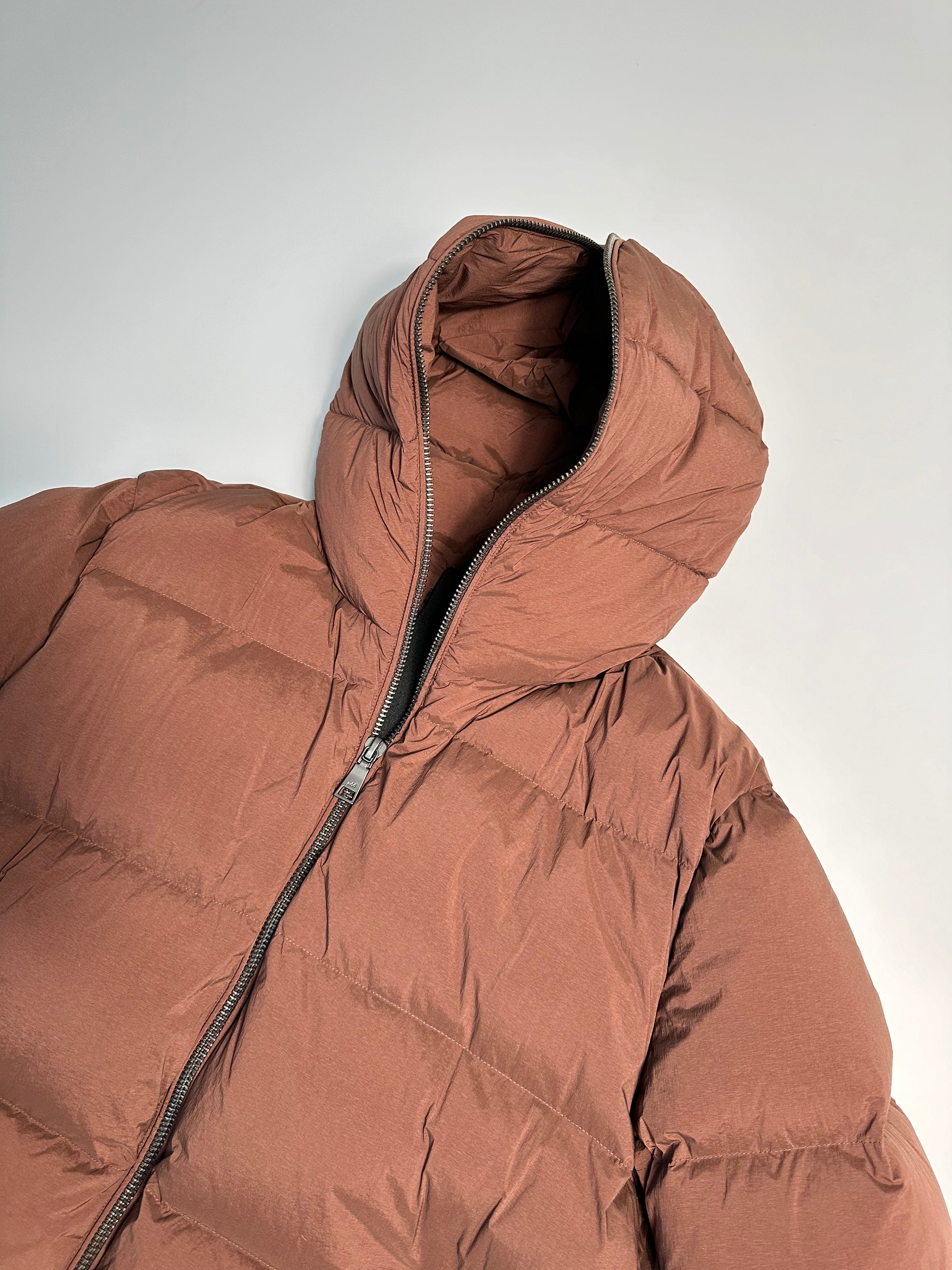 Puffy Jacket con cappuccio, chiusura zip frontale, polsini elastici e tasche con zip. Design leggero e resistente per un look invernale alla moda.