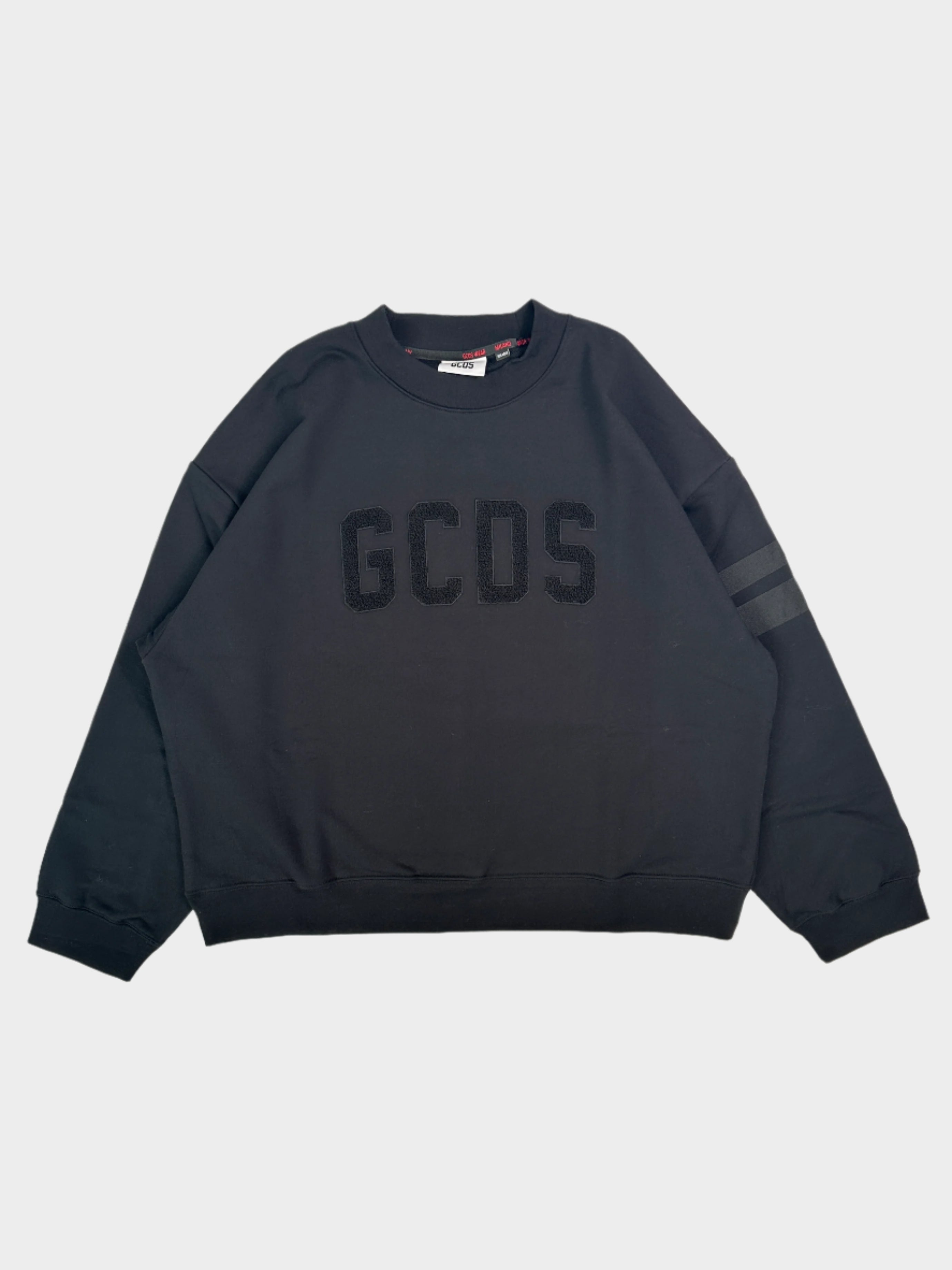 Felpa girocollo nera GCDS con logo in rilievo e dettagli streetwear. Cotone premium e fit rilassato. Acquista ora su Qlhype!