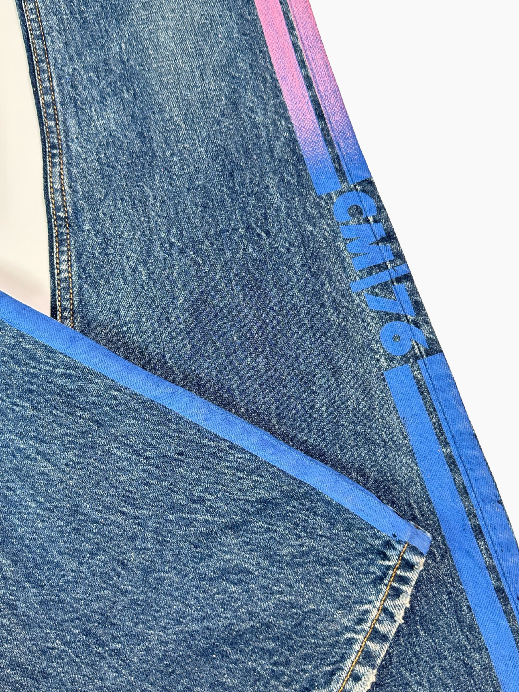 Dettaglio bande laterali a contrasto dei jeans svasati blu in basso