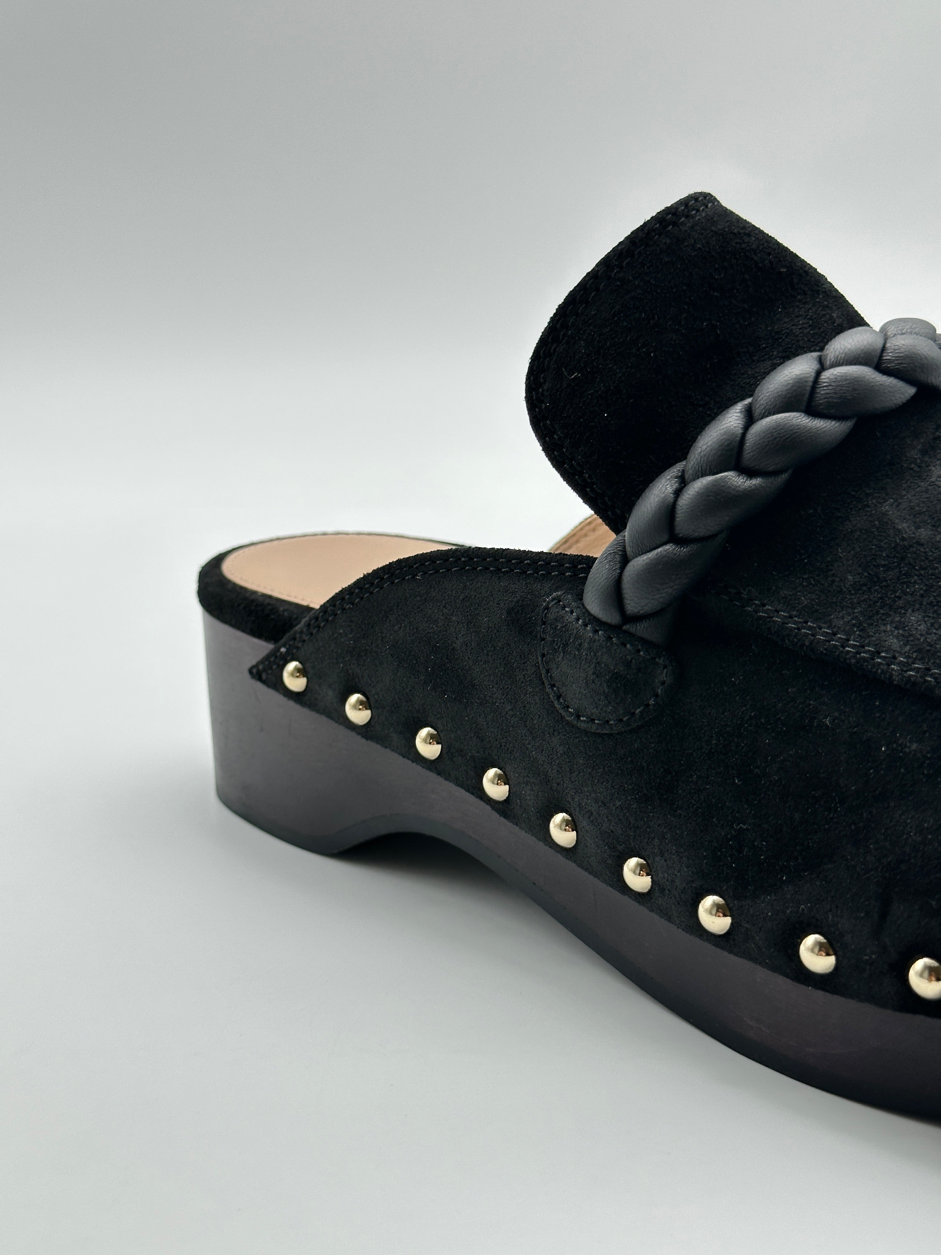 Suede Mules con punta tonda, dettaglio in pelle intrecciata, borchie laterali e tacco di 5 cm. Eleganza e comfort.