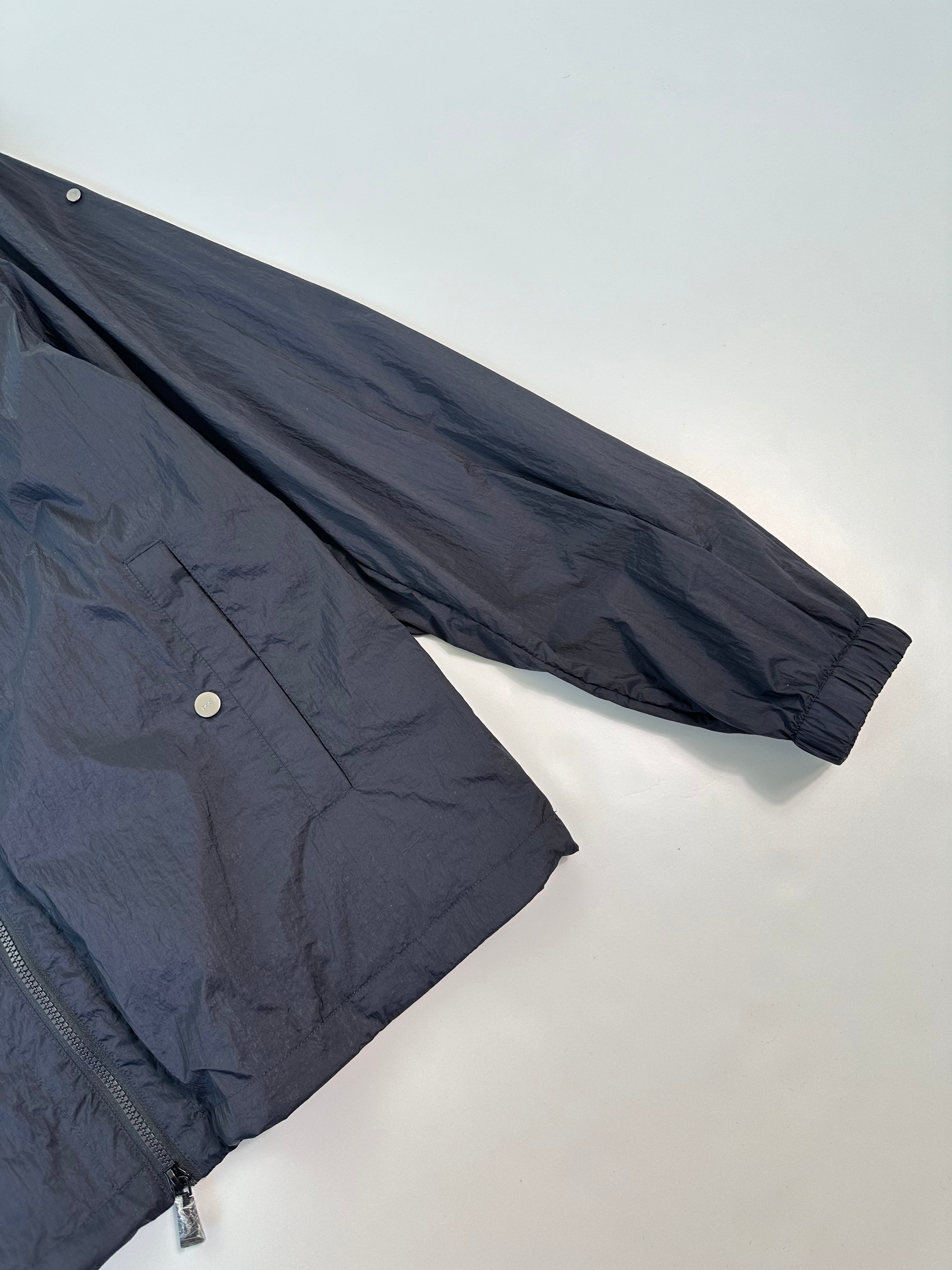 Windbreaker Jacket con cappuccio regolabile, chiusura zip, polsini elastici e tasca con bottone. Leggera e resistente per protezione contro il vento.